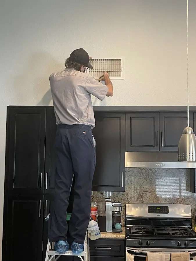 Technician inspecting an air vent during HVAC service in Napoleon